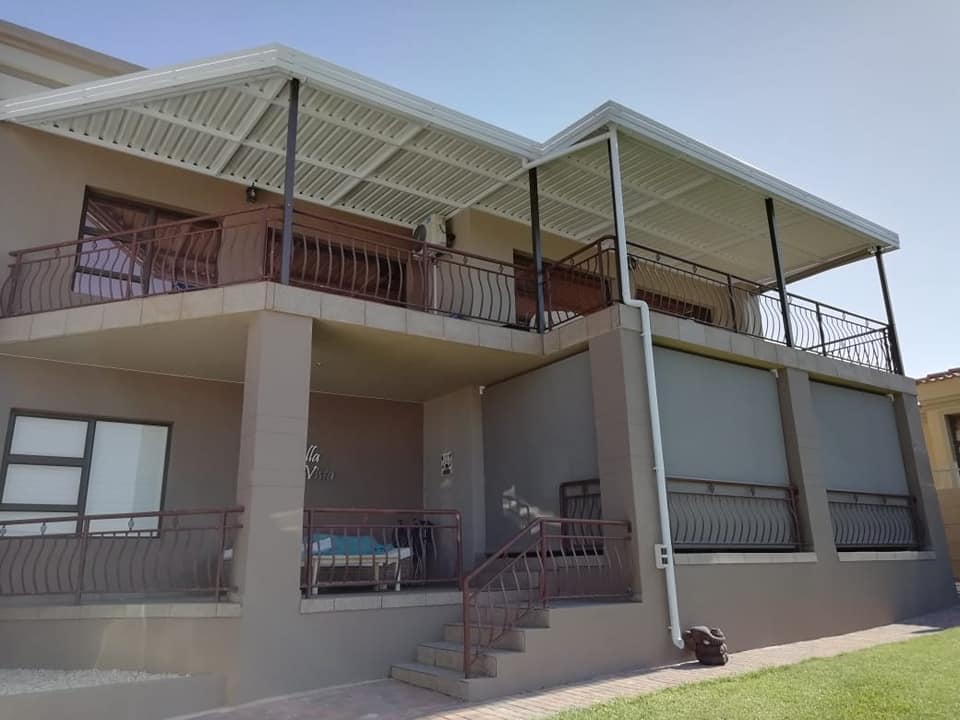 Double-storey home with white aluminium patio covers on both levels and grey roller blinds, installed by 4 Seasons in the Kouga region
